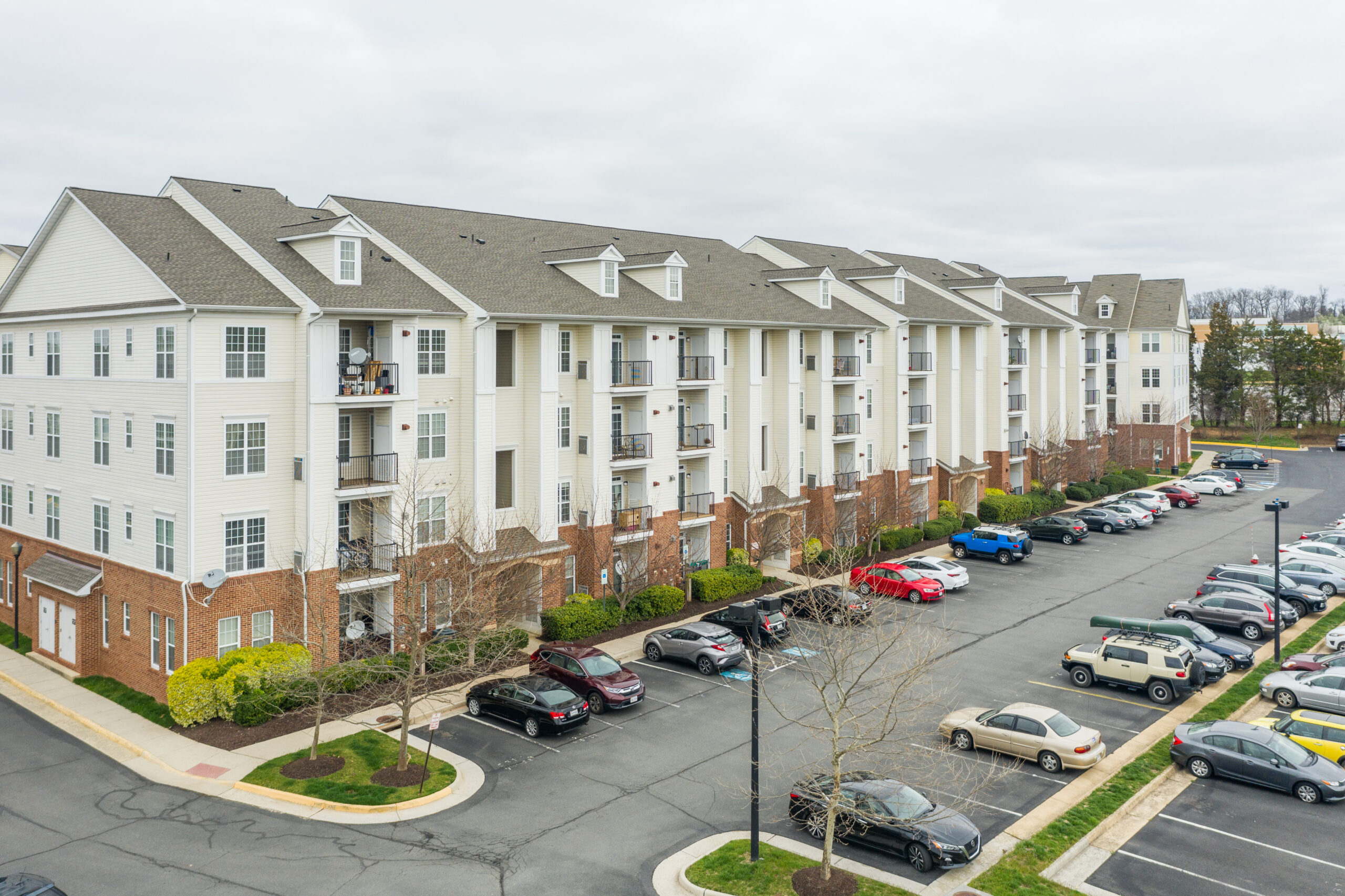 Exterior photo of multifamily property and parking lot with cars