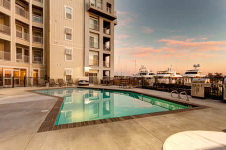 Photo of multifamily building with pool and yachts in the background