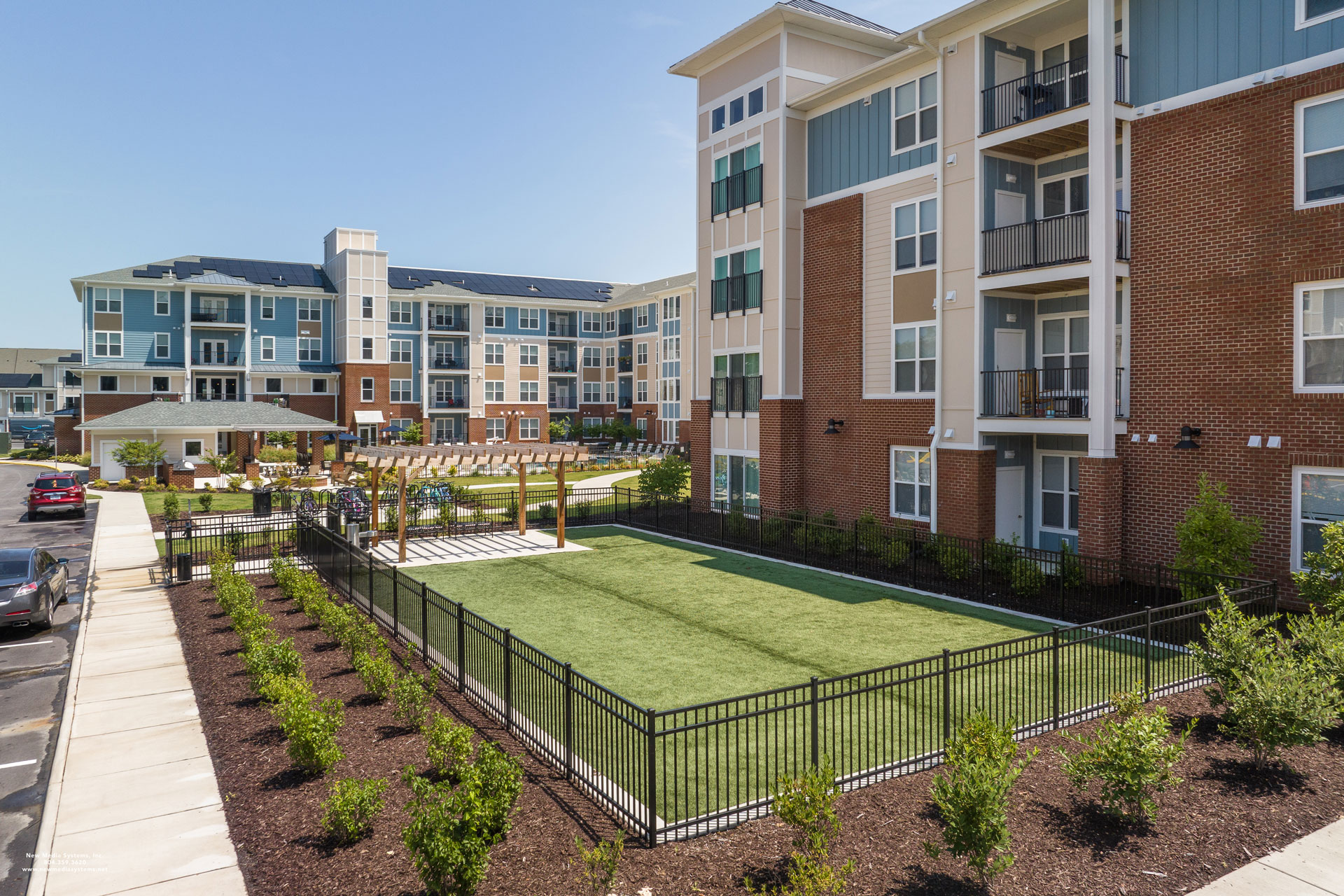 Photo of a flowerbed and fences grassy area with the exterior of the multifamily complex