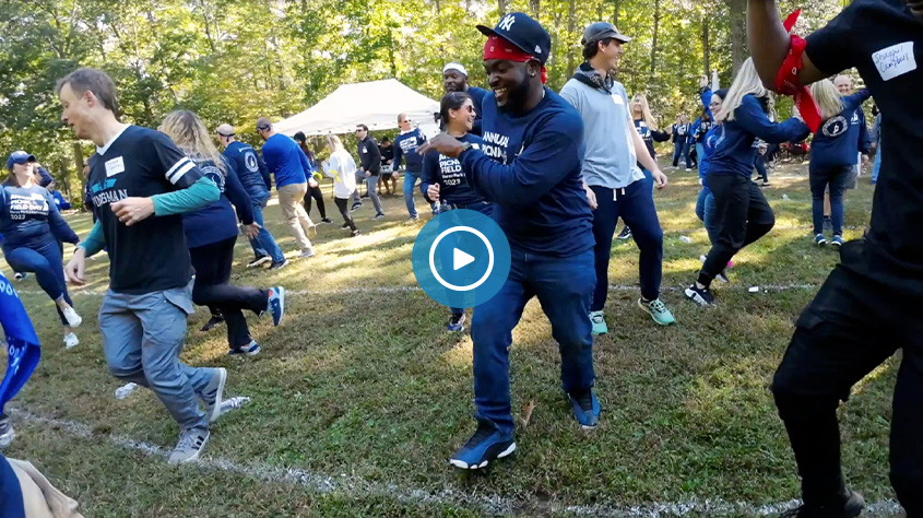 vidoe freeze frame of people dancing outside at event with play button