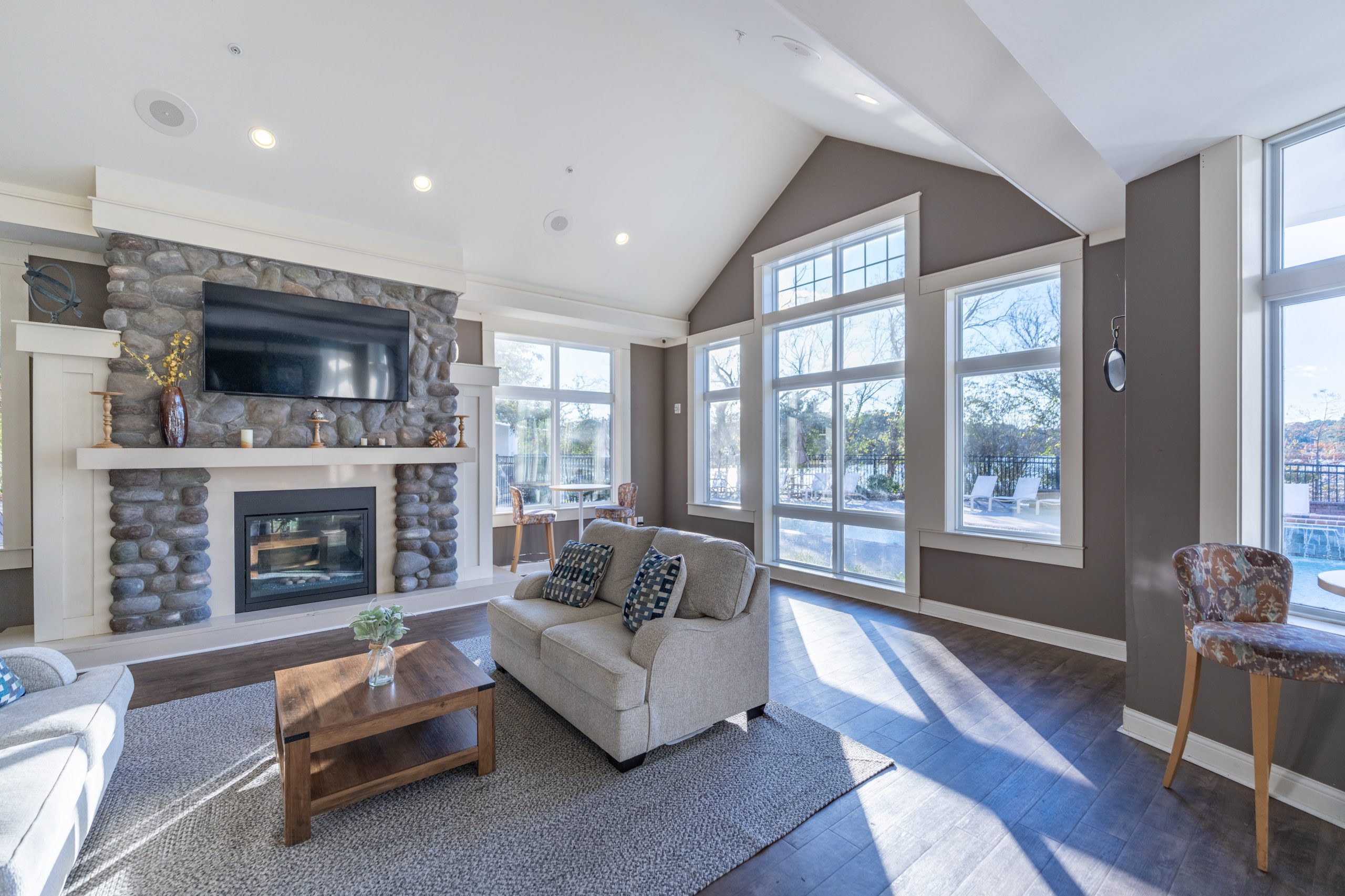 Living room with a stone fireplace, large windows, and a cozy seating arrangement featuring a sofa and coffee table.